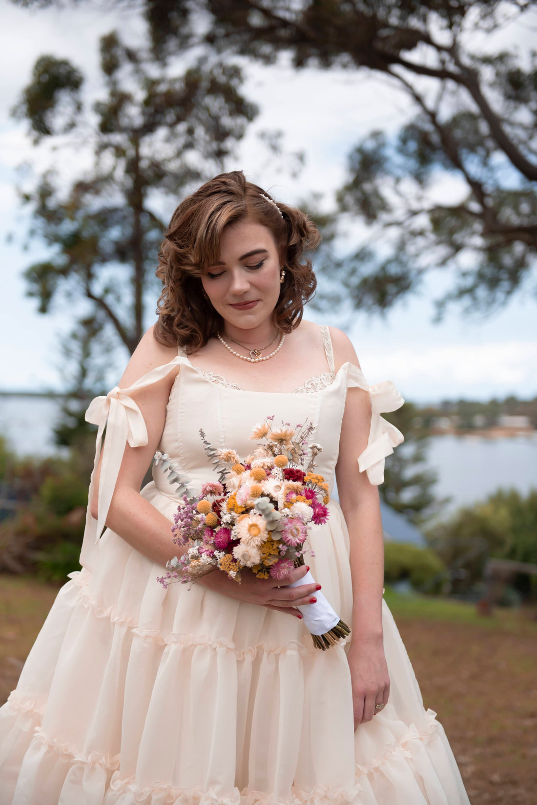 This image showcases a gorgeous flower wedding bouquet in soft pastel colours accented with eucalyptus leaves and textured fillers. The arrangement captures a boho-chic aesthetic, perfect for a rustic wedding or outdoor ceremony.