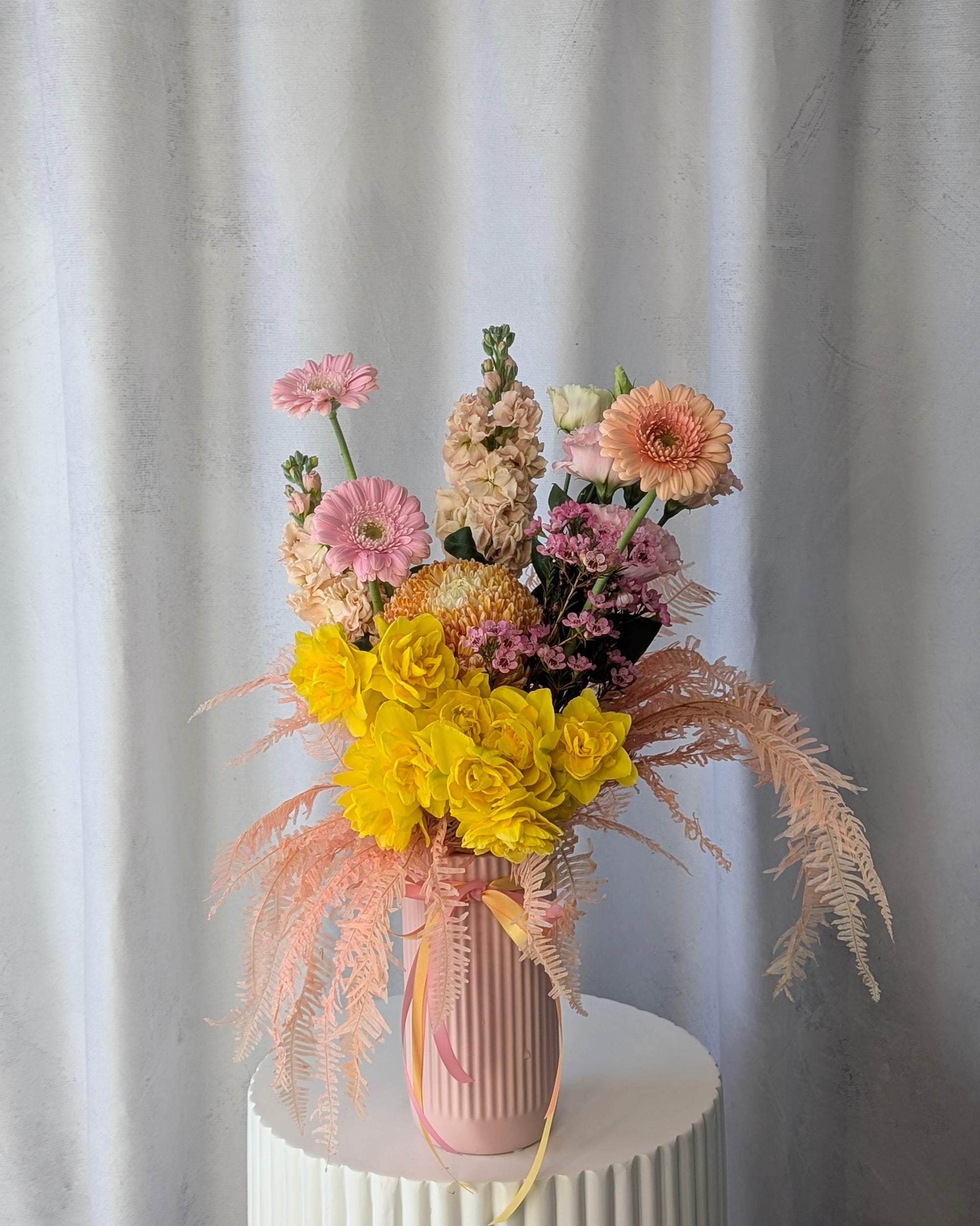 Bouquet of flowers in a pink vase against a white curtain background for delivery in Melbourne. 